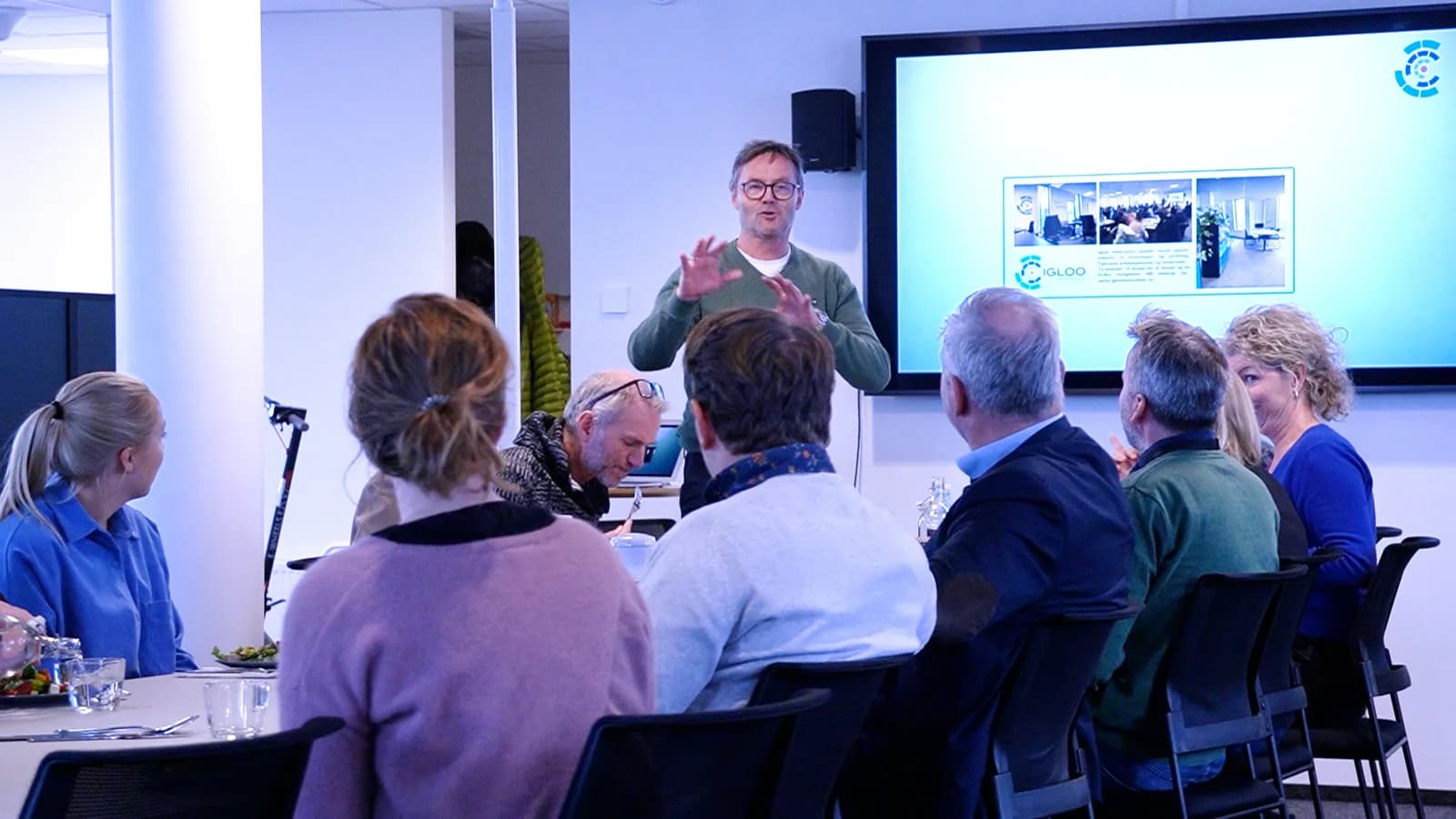 Participants gathered around a table during a presentation at Igloo Day.